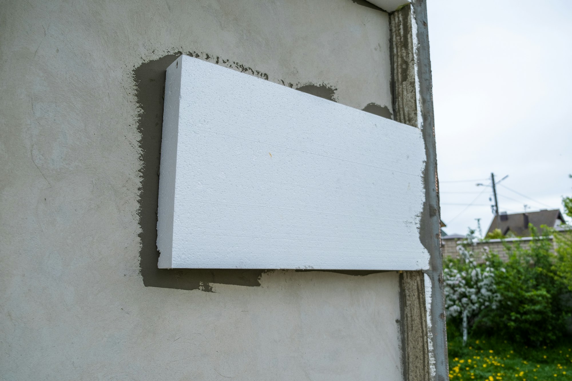 Installation of styrofoam insulation sheets on house facade wall for thermal protection.